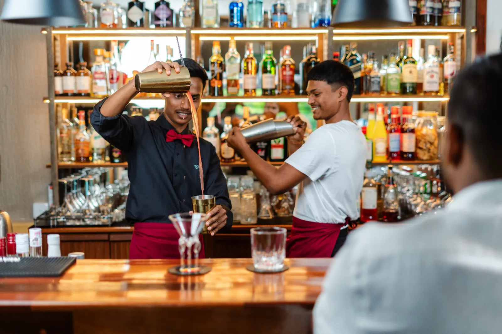 Two bartenders working the lit back bar