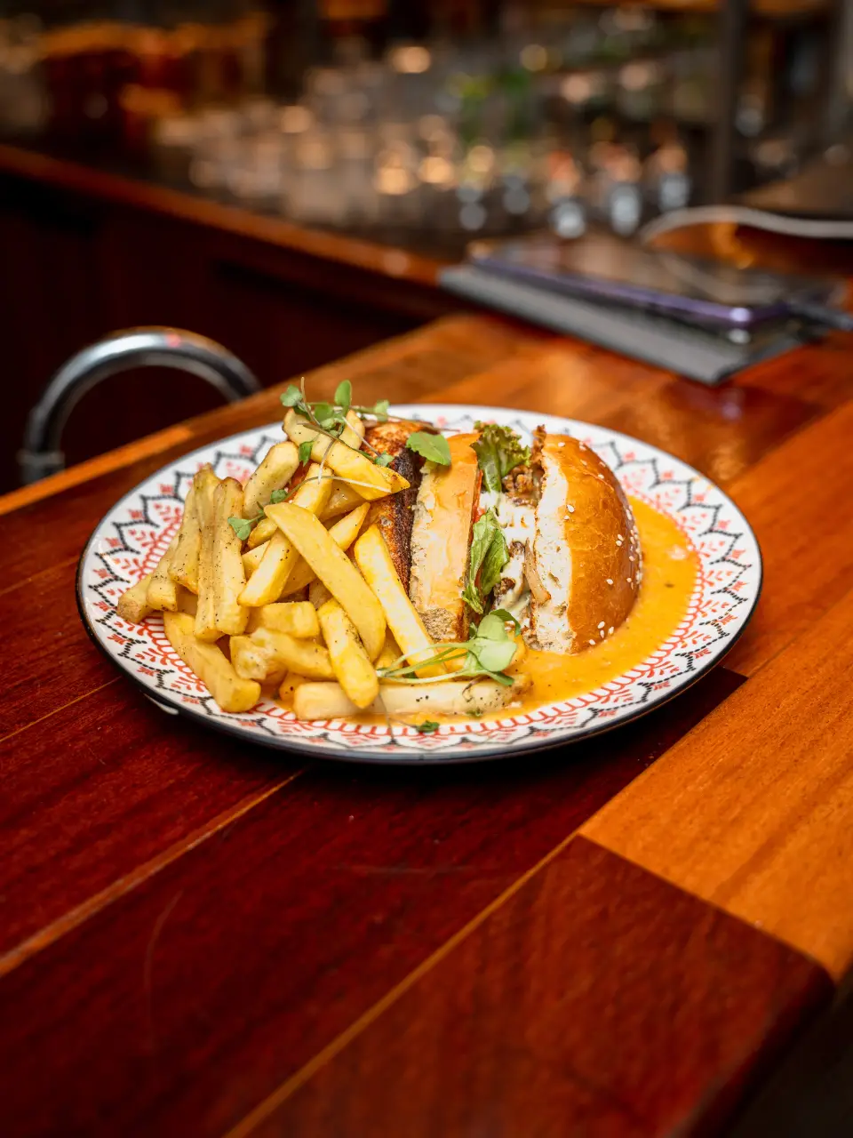 A burger with fries and sauce on the bar