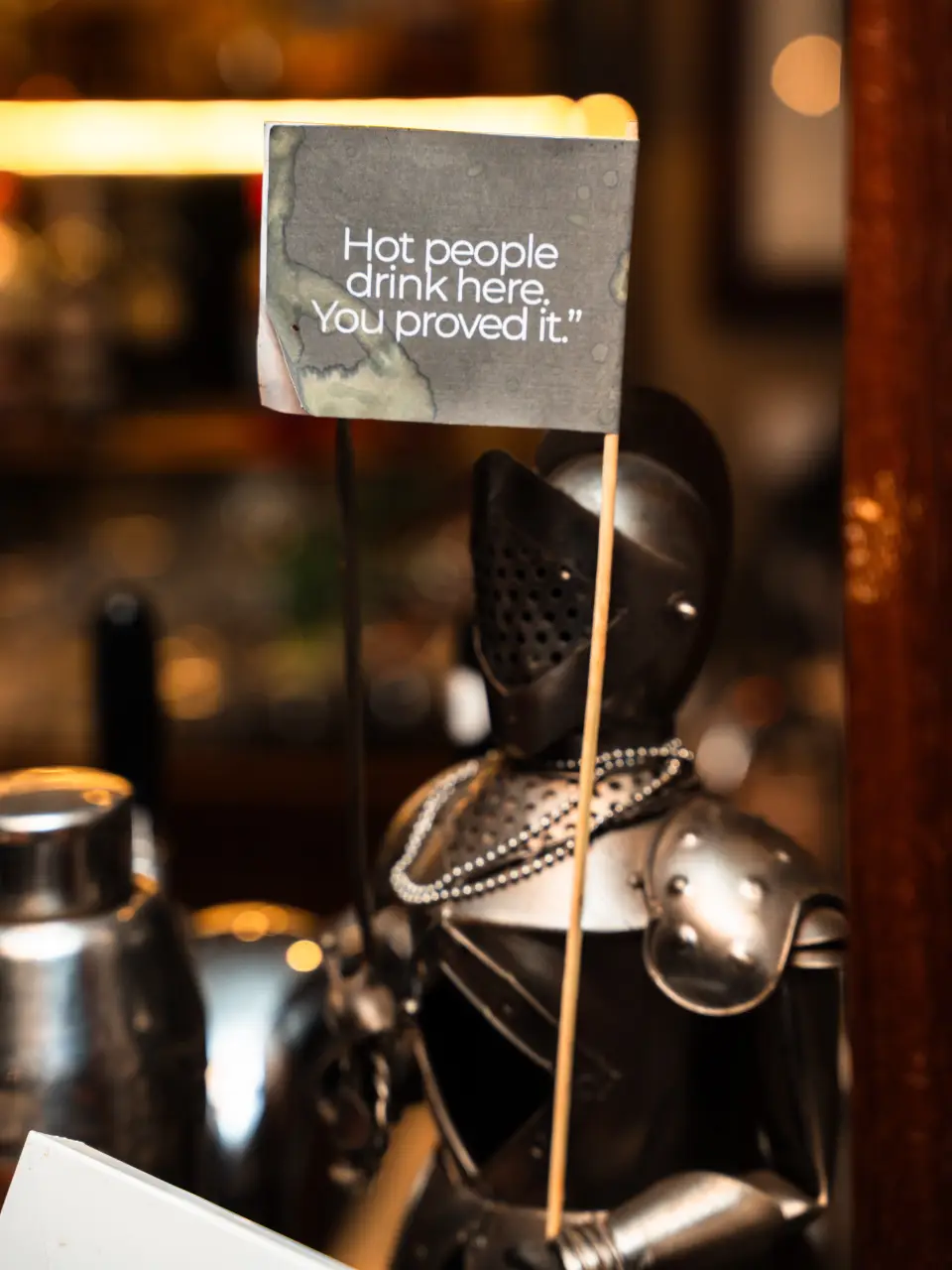 A small knight on the bar holding a flag: Hot people drink here