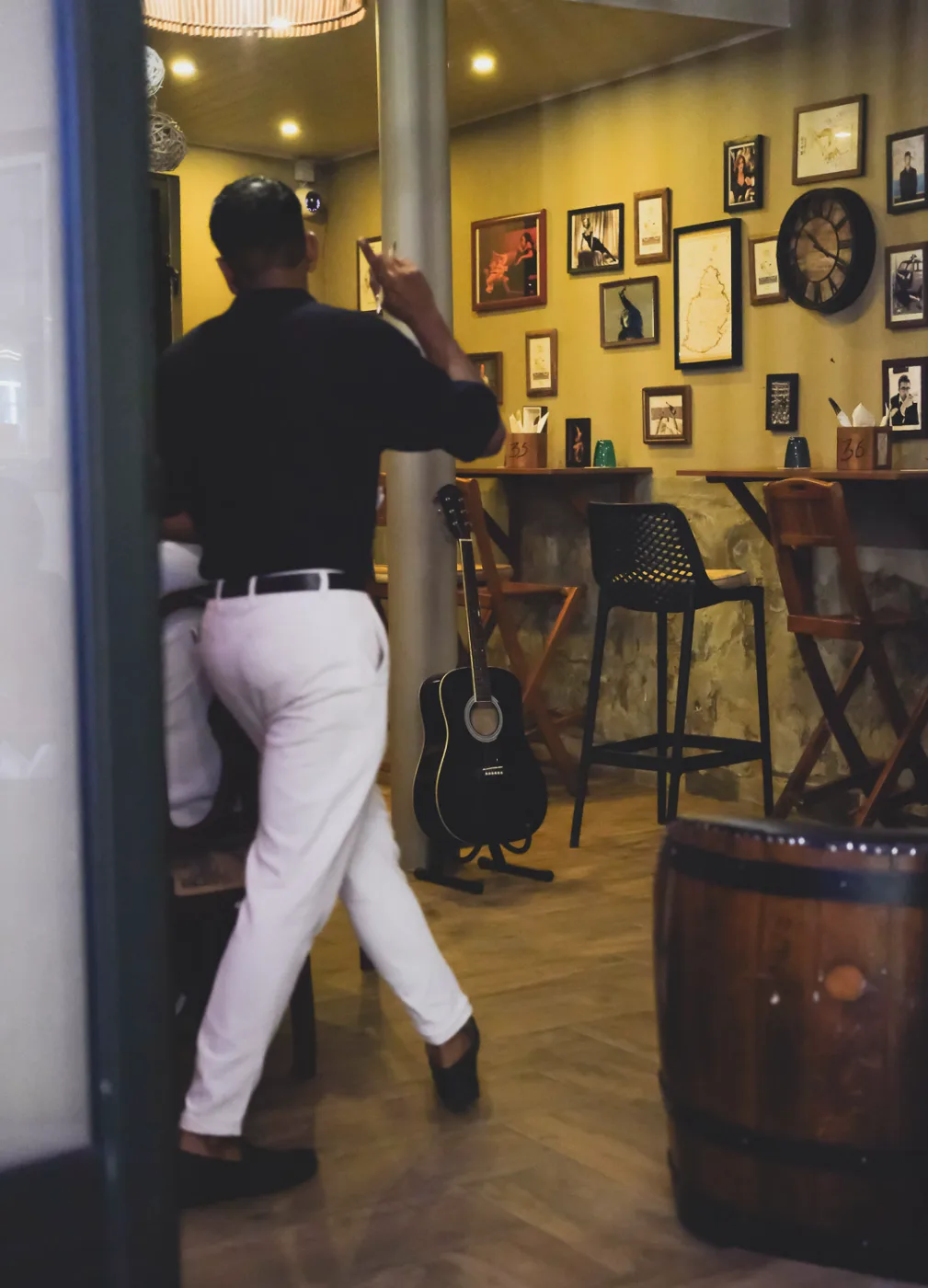 Amigo Bar & Bistro room, framed pictures, a barrel and an acoustic guitar